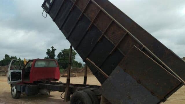 Dump truck with its bed raised, unloading debris