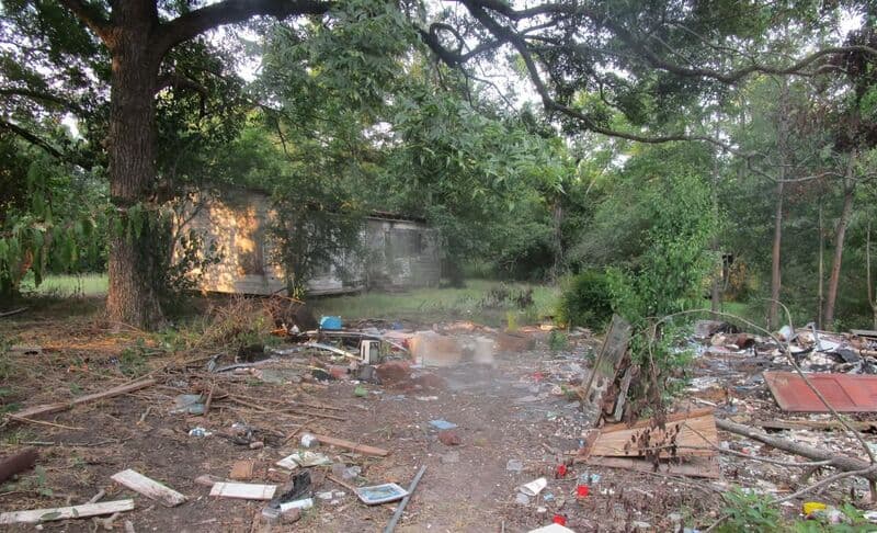 Dumped trash and debris spread across a wooded lot